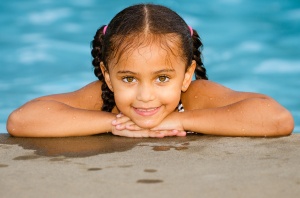 Portrait of happy pretty mixed race child by side of pool